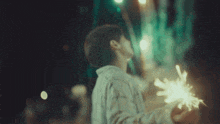 a man is holding a sparkler in his hand and looking up at it