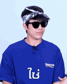 a man wearing sunglasses and a blue shirt that says balenciaga on it