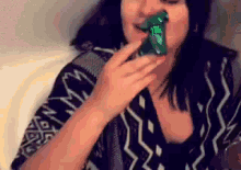 a woman in a black and white sweater is eating a green candy