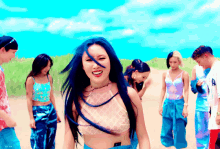 a woman with blue hair is smiling in front of a group of people on a beach