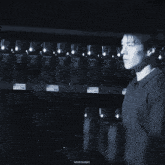 a black and white photo of a man standing in front of a shelf with bottles of wine on it