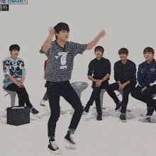 a group of young men are sitting on stools and one of them is wearing a striped shirt with a bunny on it