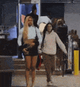 a woman in a white sweatshirt is walking with a woman in a short skirt
