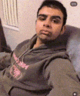 a man in a hoodie is sitting in a chair and looking at the camera .