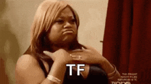 a woman is making a funny face while holding her hands to her chest and saying tf .