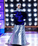 a drag queen is wearing a blue and silver dress