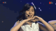 a woman in a white dress is dancing in front of a sign that says ' live '