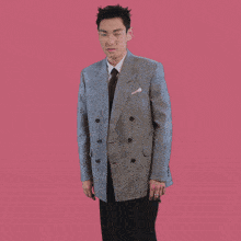 a man in a suit and tie is dancing in front of a pink background