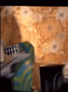 a blurred image of a room with a floral wallpaper and a box that says ' coca cola ' on it