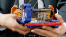 a person is holding a toy in their hands that has a red and blue item on it