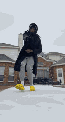 a man wearing yellow crocs is standing in the snow