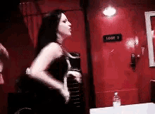 a woman in a black dress is standing in front of a red door with a sign that says lodge 3