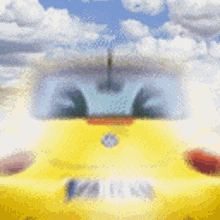a yellow car is driving down a road with clouds in the background .