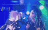 two women are singing into microphones on a stage with a blue background