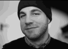 a man with a beard is wearing a black beanie and smiling