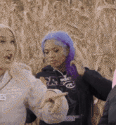 a woman with purple hair is pointing at another woman