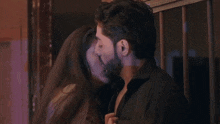 a man and a woman are kissing and looking at each other in a room .