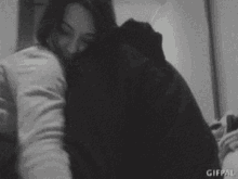 a black and white photo of a man and woman hugging each other .
