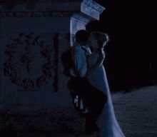 a man and a woman are kissing in front of a statue