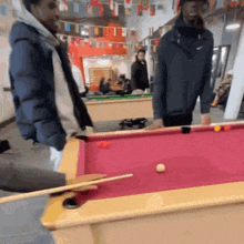 two men are playing pool in a room with many flags