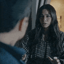 a woman with long hair is talking to a man in a blue shirt .