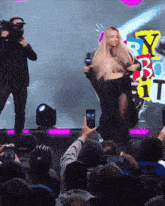 a man taking a picture of a woman on a stage with a sign that says party box 1