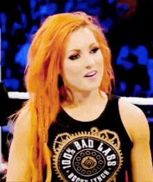 a woman with red hair is wearing a black tank top that says " bad lass "