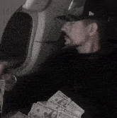 a man wearing a new york yankees hat holds a stack of money