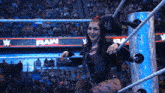 a woman is sitting in a wrestling ring with a sign that says raw on it