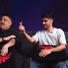 a man in a white shirt is making a heart shape with his fingers