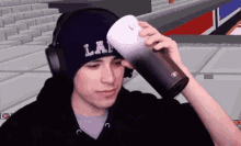 a young man wearing headphones and a beanie is holding a cup of coffee .