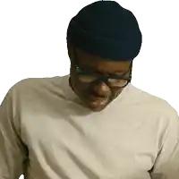 a man wearing glasses and a beanie looks down at something