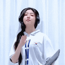 a woman wearing headphones and a white shirt with a korean flag on it is dancing .