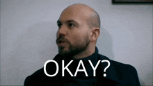 a bald man with a beard is making a funny face and saying okay .