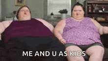 two very fat women are sitting on a couch .