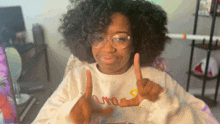a woman wearing glasses and a white sweater with the word uno on it