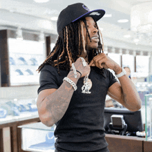 a man with dreadlocks is wearing a black shirt and a hat with the letter g on it