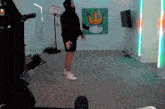 a man is standing in a living room with a basketball hoop and a painting of a crown on the wall
