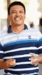 a man in a blue and white striped shirt is smiling and holding money