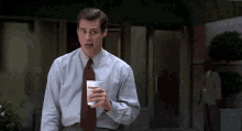 a man in a blue shirt and red tie is holding a cup that says mcdonald 's on it