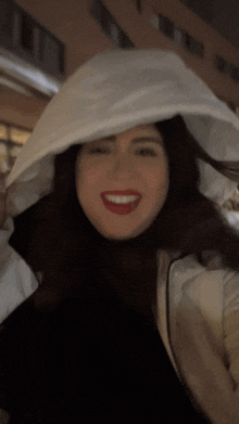 a woman is wearing a white hooded jacket and smiling