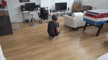 a person is sitting on the floor in a living room with a foosball table in the background .