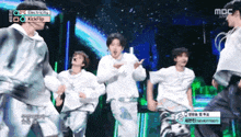 a group of young men are dancing on a stage in front of a crowd .