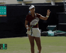 a woman holding a tennis racquet in front of a scoreboard that says wimbledon