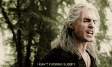 a man with long hair is standing in the woods and yelling .