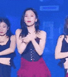 a woman in a red dress and black corset is dancing on a stage .