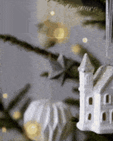 a white house ornament is hanging from a string on a christmas tree
