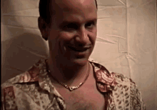 a man with a necklace around his neck is smiling and looking at the camera