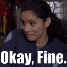 a woman in a blue jacket is sitting in an ambulance with the words okay fine .
