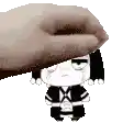 a hand is putting a cartoon character on top of a person 's head .